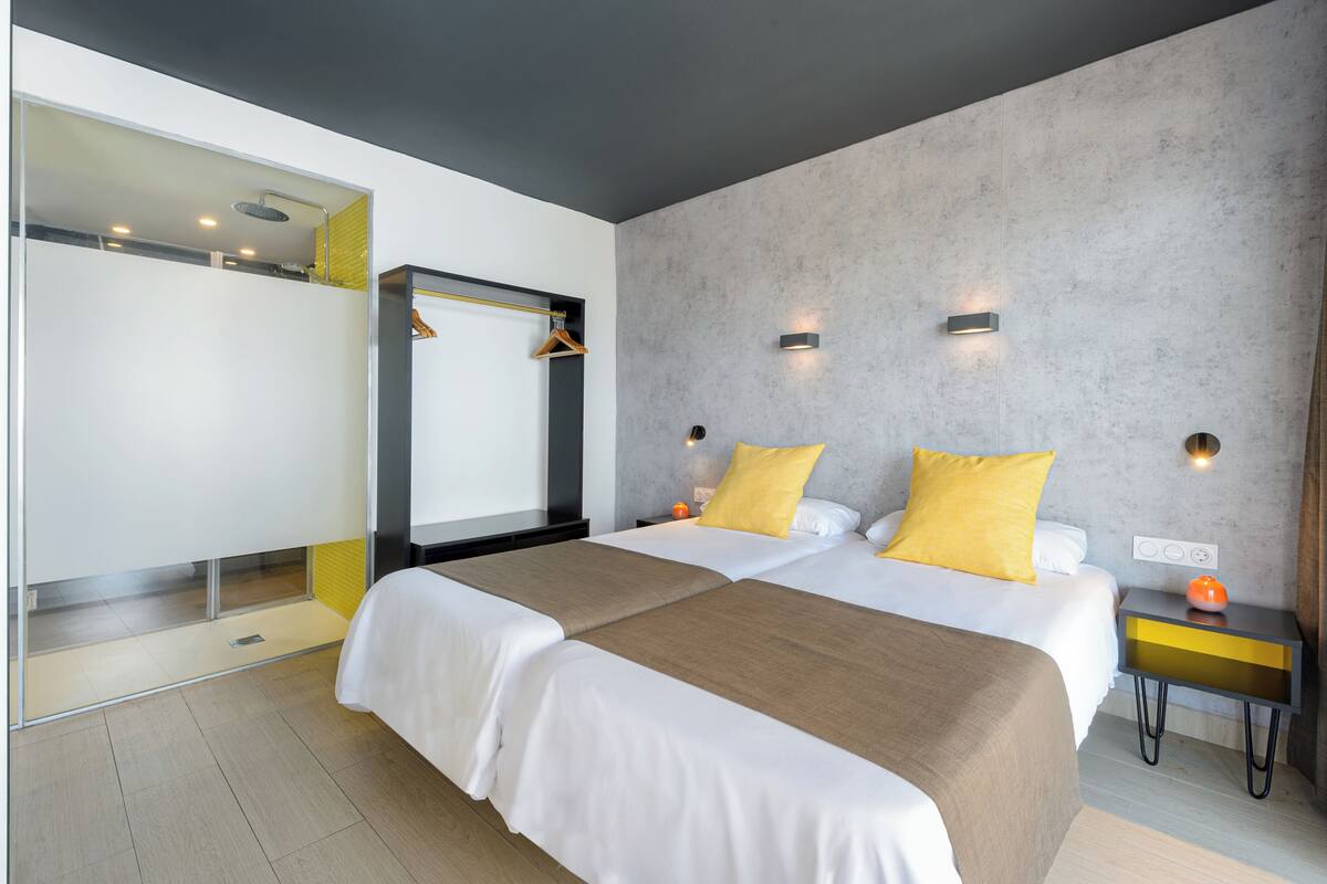 A modern hotel room with a large bed, a walk-in closet, and a bathroom with a shower.