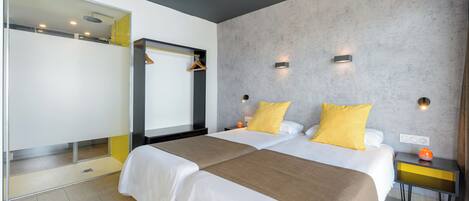 Una habitación de hotel moderna con una cama grande, un vestidor y un baño con ducha.