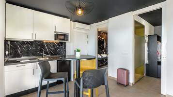 Una cocina moderna con armarios blancos, un salpicadero de mármol negro y una mesa redonda de comedor con dos sillas.