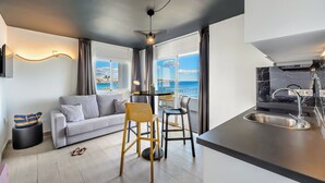 Een moderne woonkamer met een bank, twee stoelen, een kleine tafel en een keuken met een spoelbak.