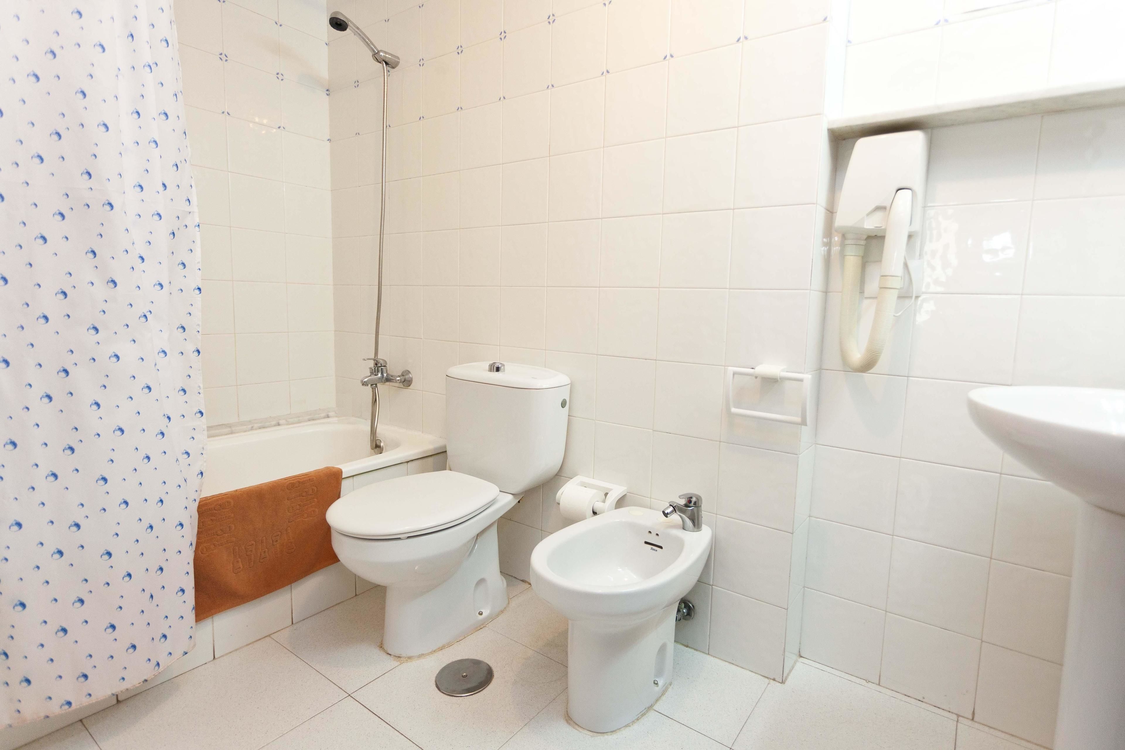Un baño con inodoro, bidé y ducha.