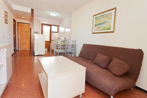 A living room with a brown sofa, a white coffee table, and a dining area with a table and chairs.