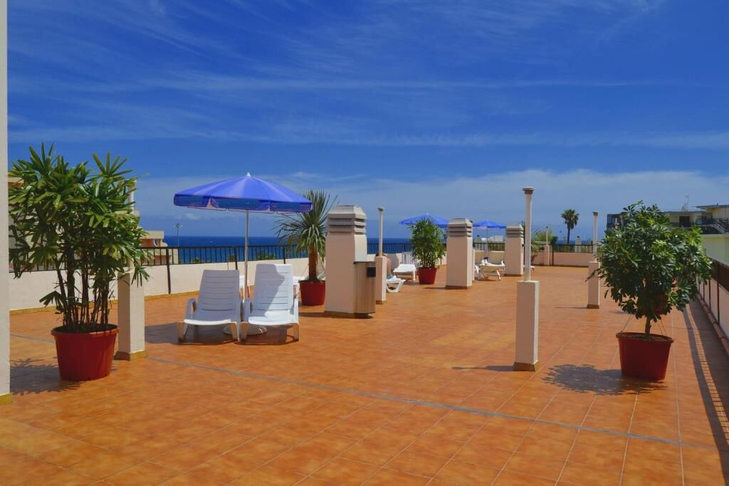 Una terraza en la azotea con sillones de descanso, plantas en macetas y sombrillas.