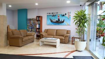 Un salon moderne avec deux canapés marron, une table basse, une bibliothèque et un grand tableau représentant une gondole, accroché au mur.
