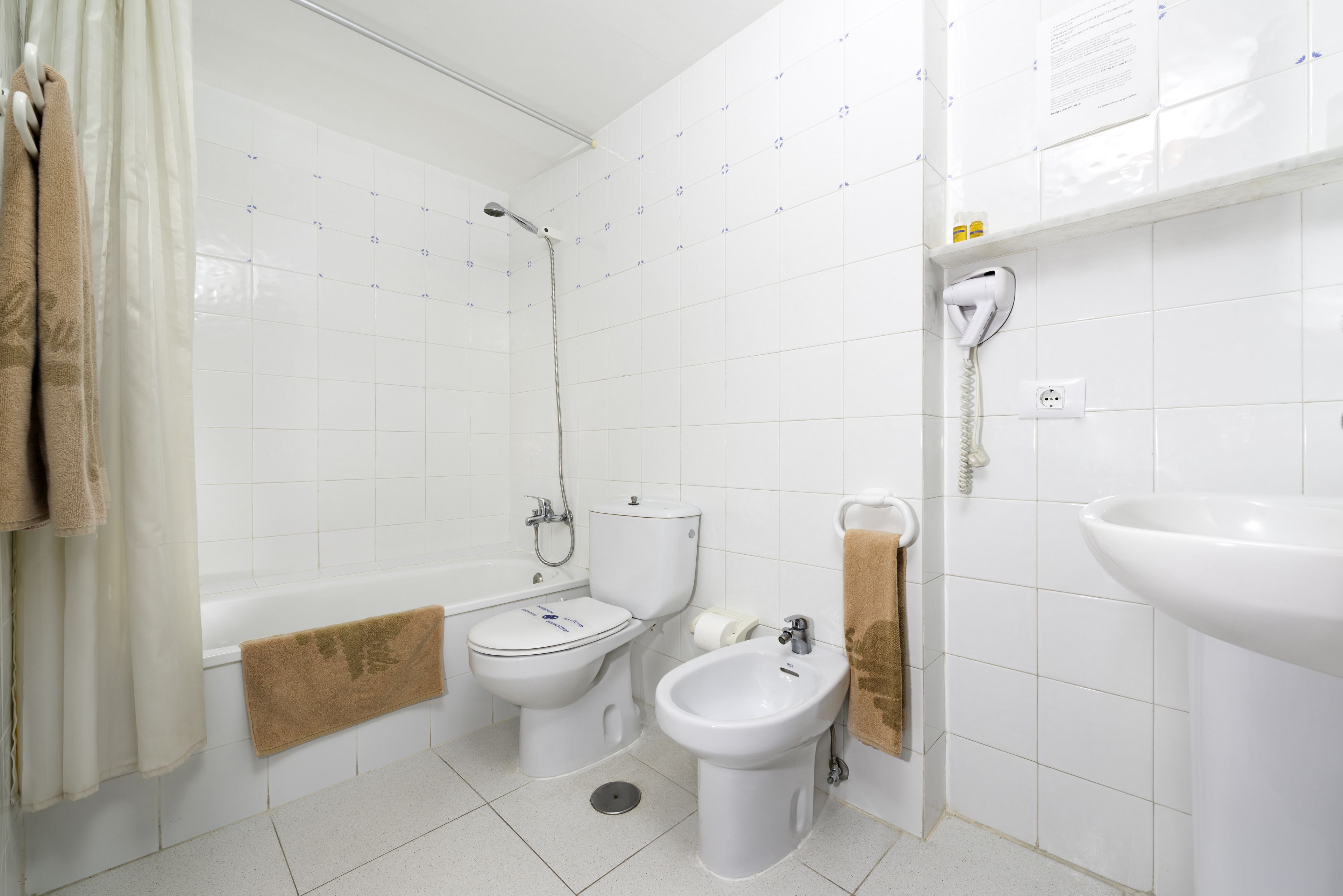 A bathroom with a bathtub, toilet, bidet, and sink.