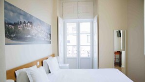 Habitación de hotel con una cama grande, un cuadro en la pared y vistas a través de la puerta.