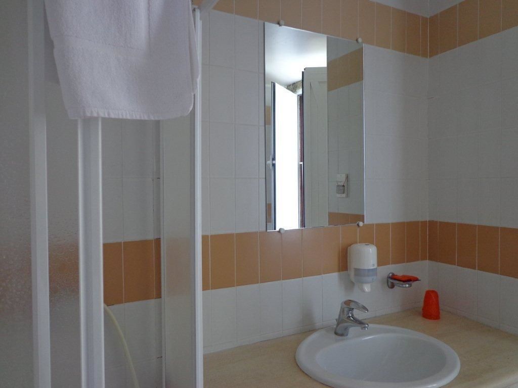 A bathroom with a white sink, a mirror, and a shower enclosure.