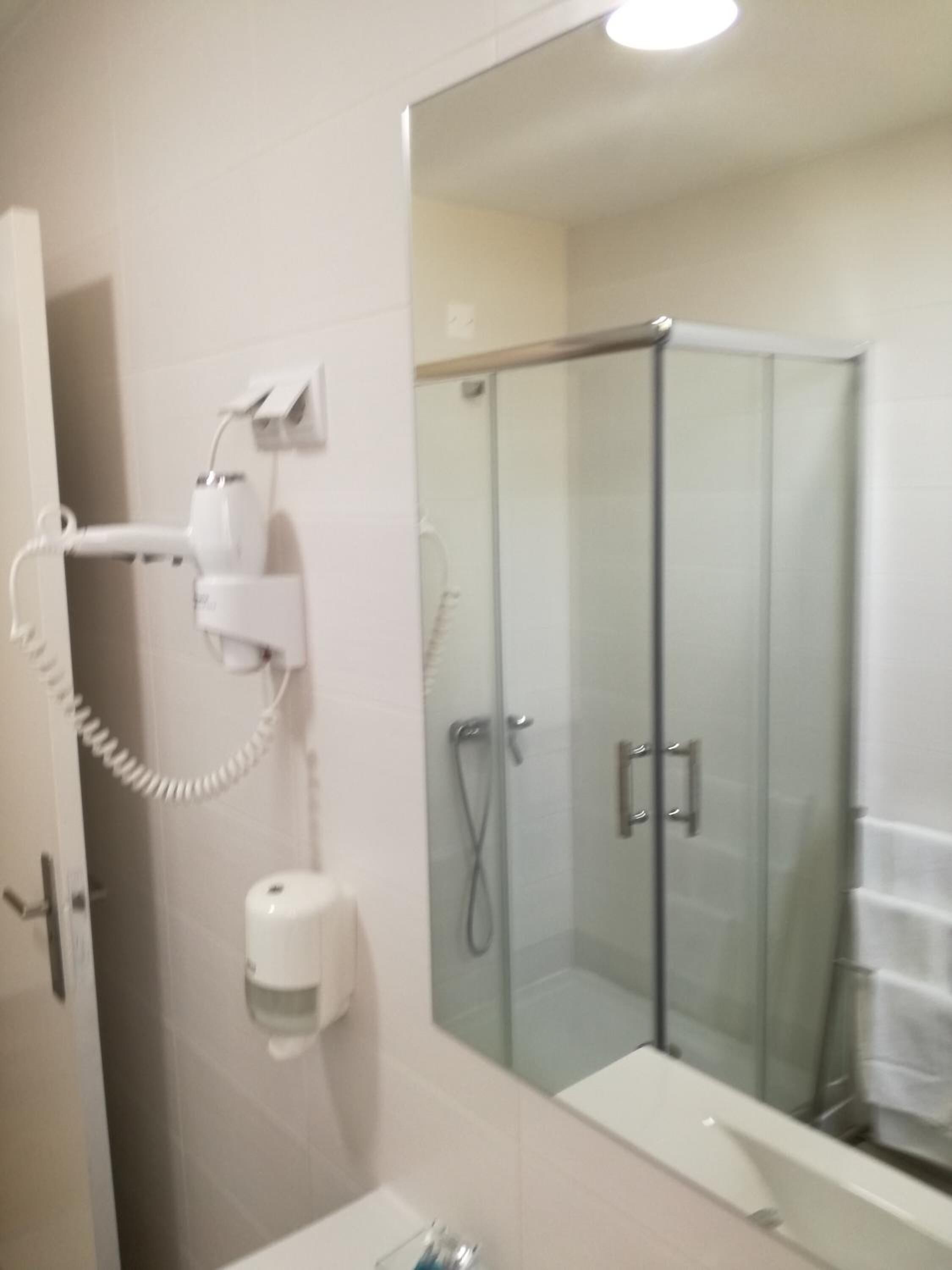 A bathroom with a glass shower enclosure, a toilet, and a sink.