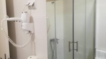 A bathroom with a glass shower enclosure, a toilet, and a sink.