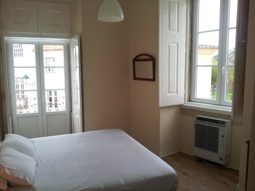 Una habitación con una cama, una ventana y un equipo de aire acondicionado.