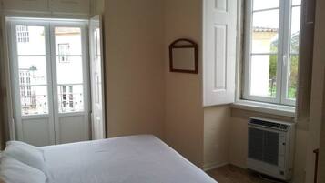 Una habitación con una cama, una ventana y un equipo de aire acondicionado.