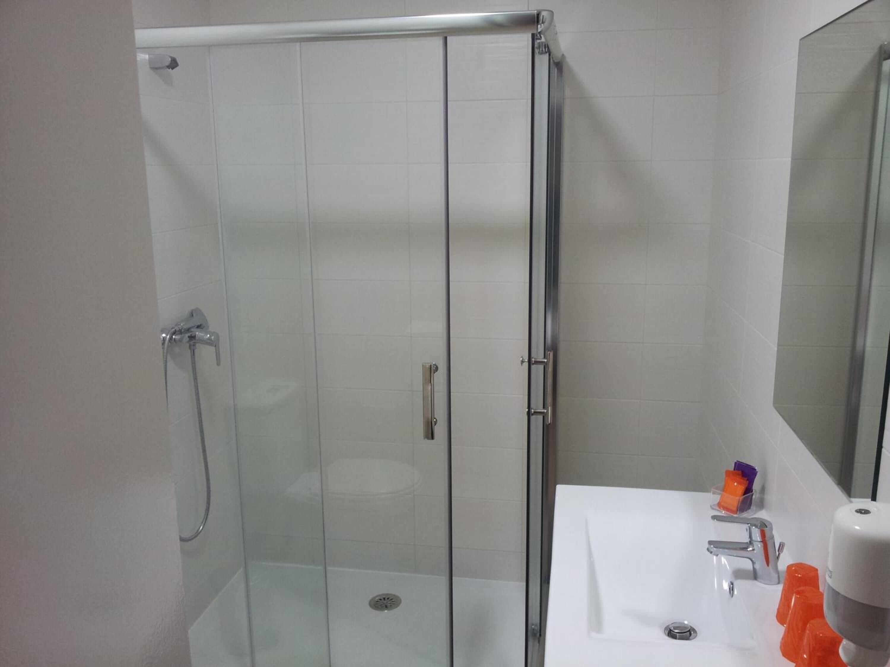 A glass-enclosed shower with a white sink and a mirror.