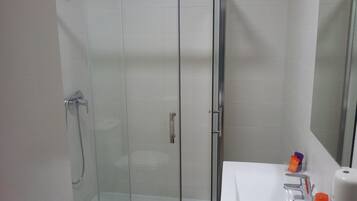 A glass-enclosed shower with a white sink and a mirror.