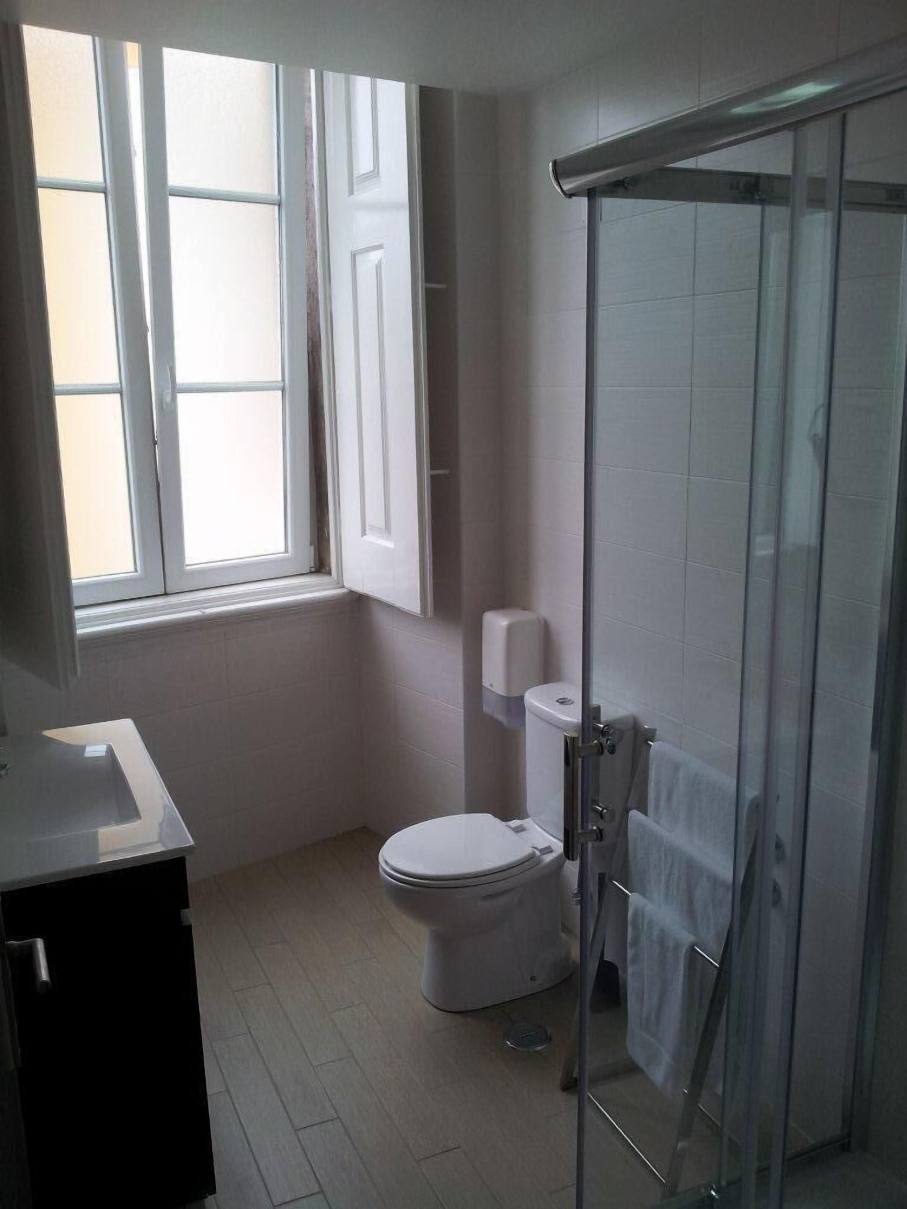 A bathroom with a toilet, a glass shower enclosure, and a window.