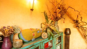 Un intérieur rustique avec un meuble en bois, un vase contenant des fleurs séchées, une plante décorative et un luminaire fixé au mur.