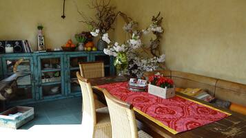 A dining area with a table for four, set with a tablecloth and a centerpiece of flowers.