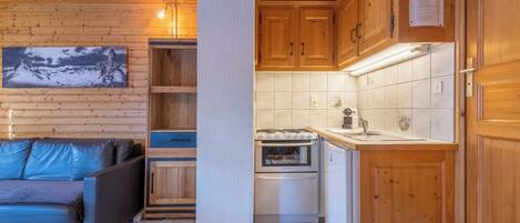 A compact kitchen with wooden cabinets, a built-in oven, and a sink.