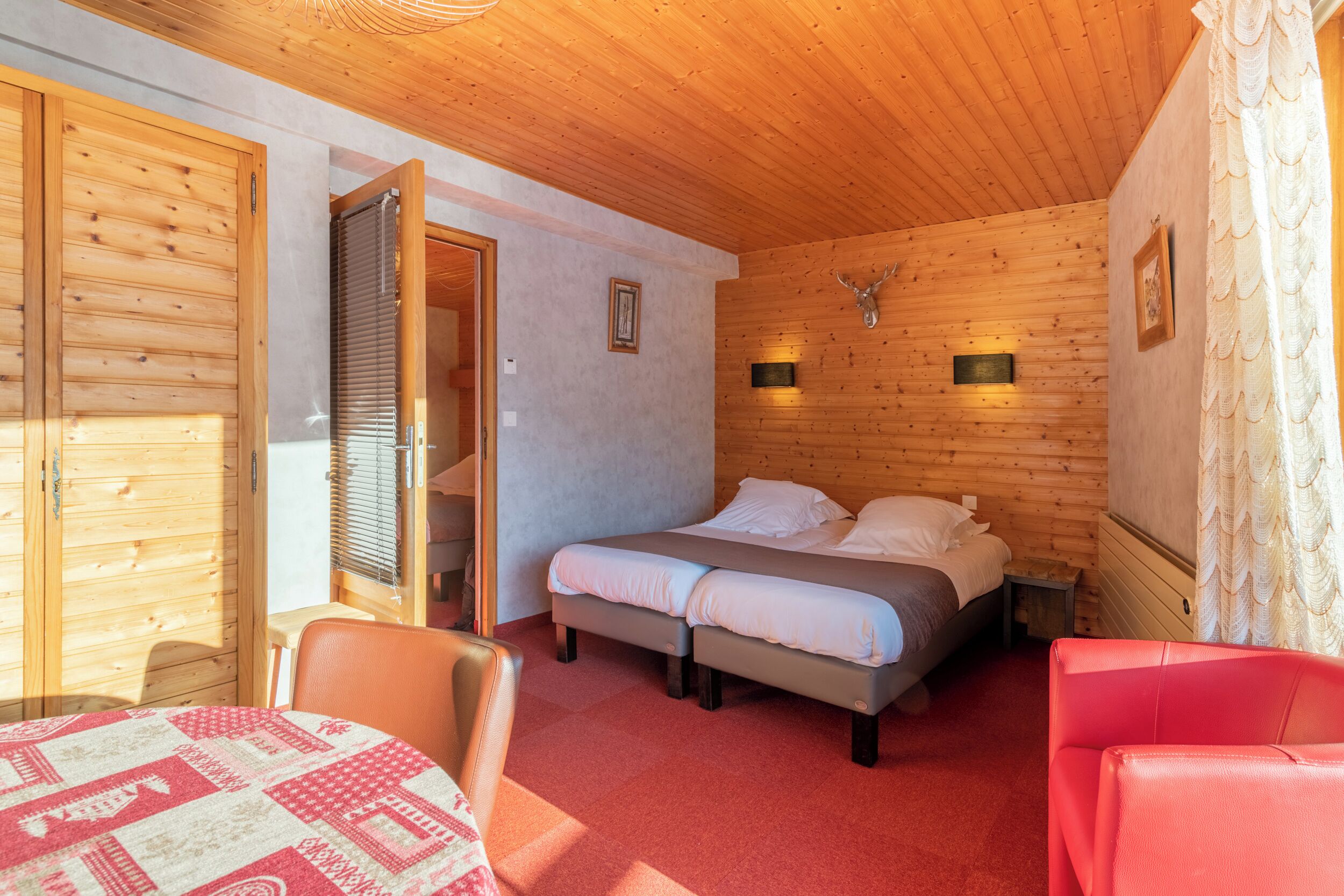 Een houten kamer met twee bedden, een tafel en een stoel.
