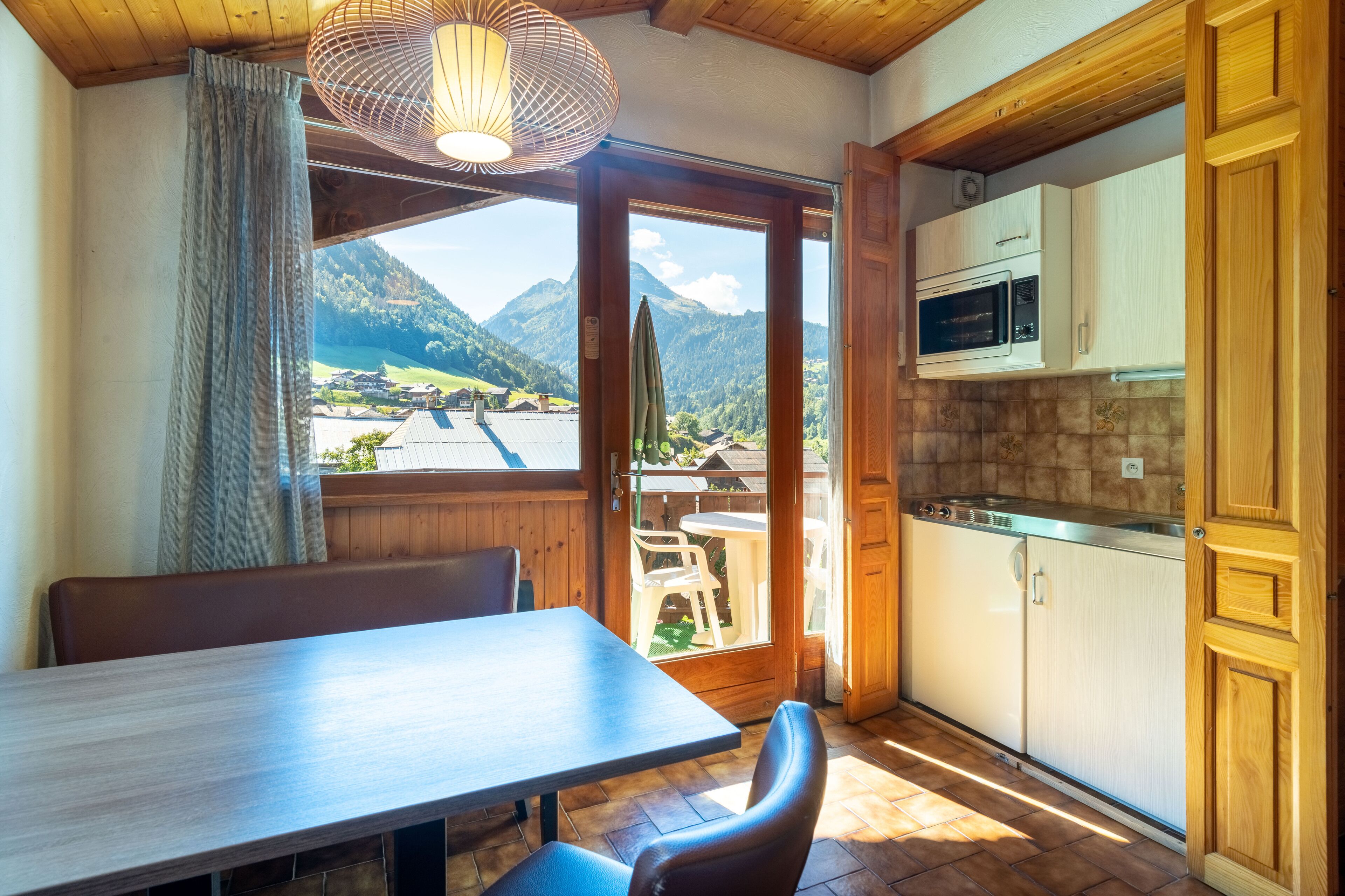 Un comedor con mesa y sillas, vistas a las montañas, y una cocina con armarios de madera y un microondas.