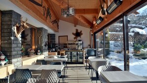 Een gezellig restaurant met houten inrichting, stenen muren en uitzicht op een besneeerd landschap.