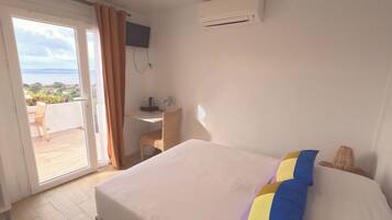 Ein Hotelzimmer mit Bett, Schreibtisch, Klimaanlage und Meerblick.