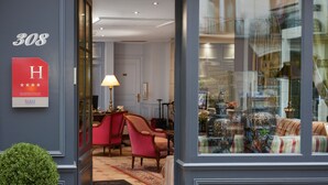 A hotel entrance with a number sign, a reception desk, and a view of the interior through a glass door. - Le Relais Saint Honoré (Paris)