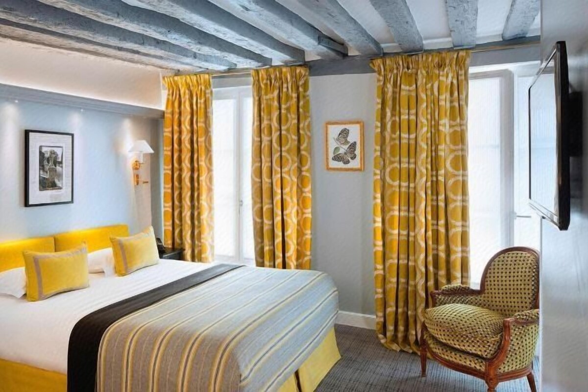 A hotel room with a bed, a chair, and curtains.