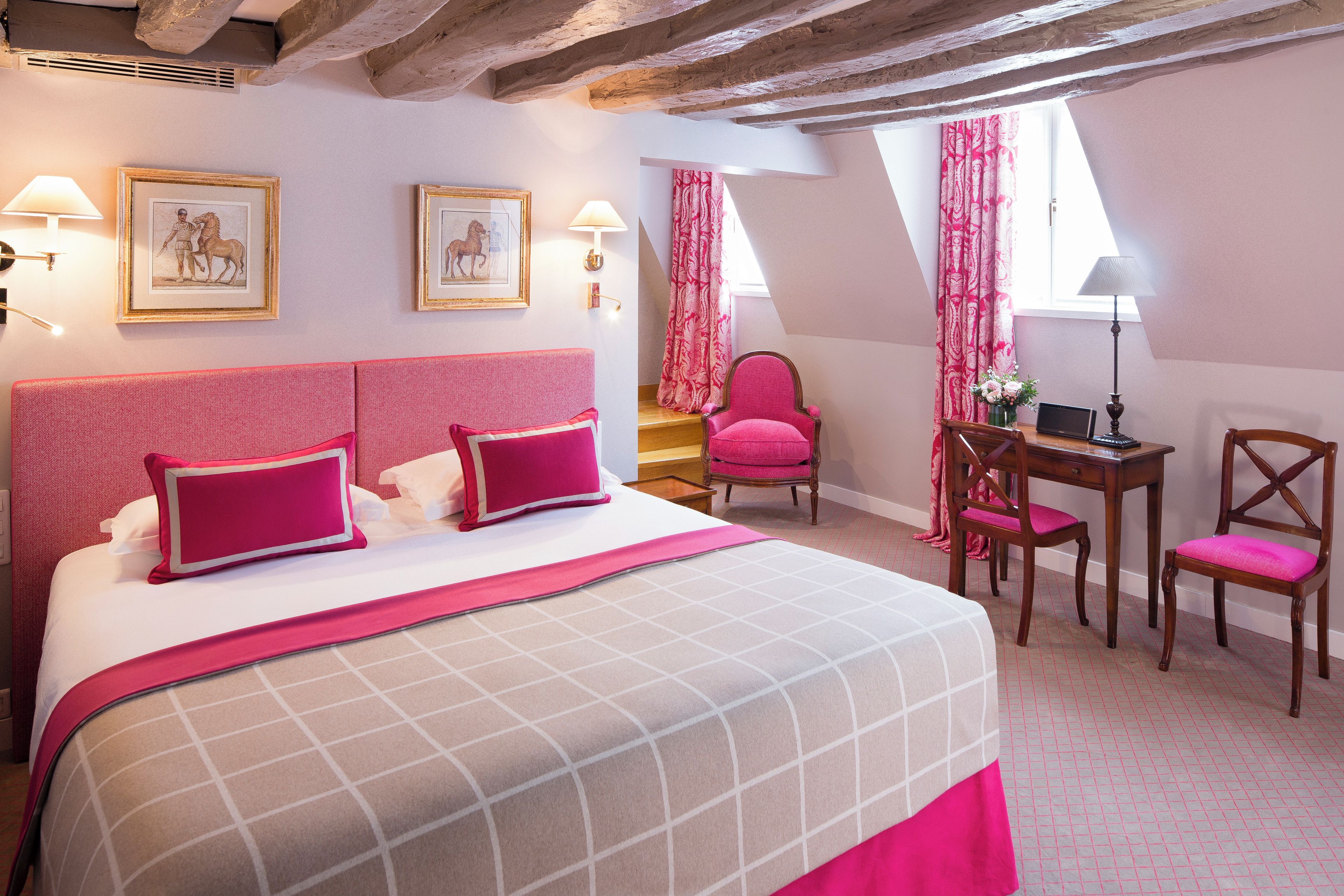 A hotel room with a large bed, two bedside tables, a desk, and a chair.