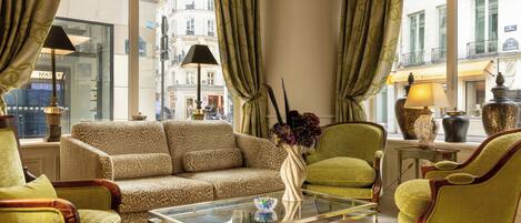 A well-lit living room with a sofa, armchairs, a coffee table, and a vase of flowers.