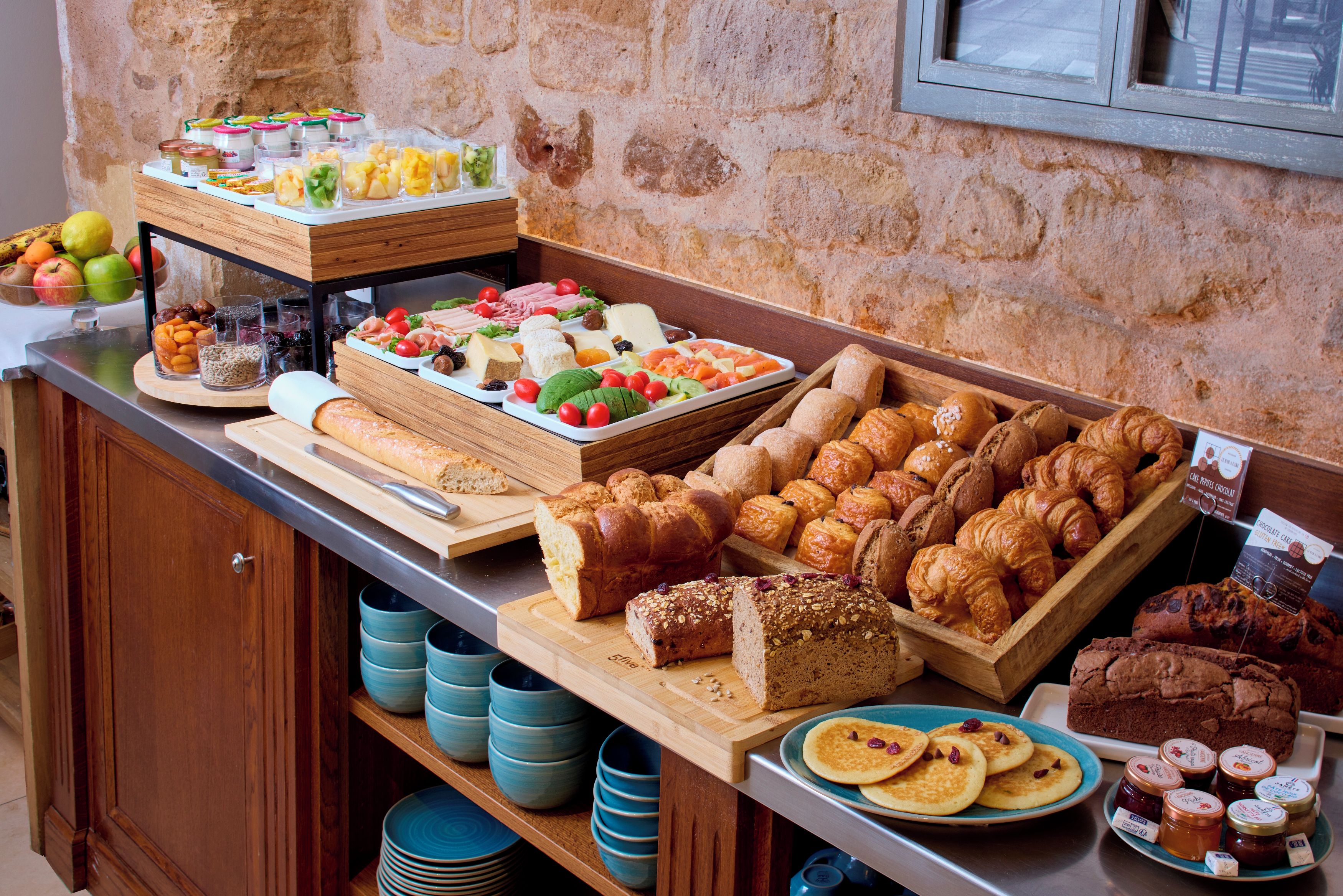 Een buffet met diverse gerechten, waaronder brood, gebak en fruit.