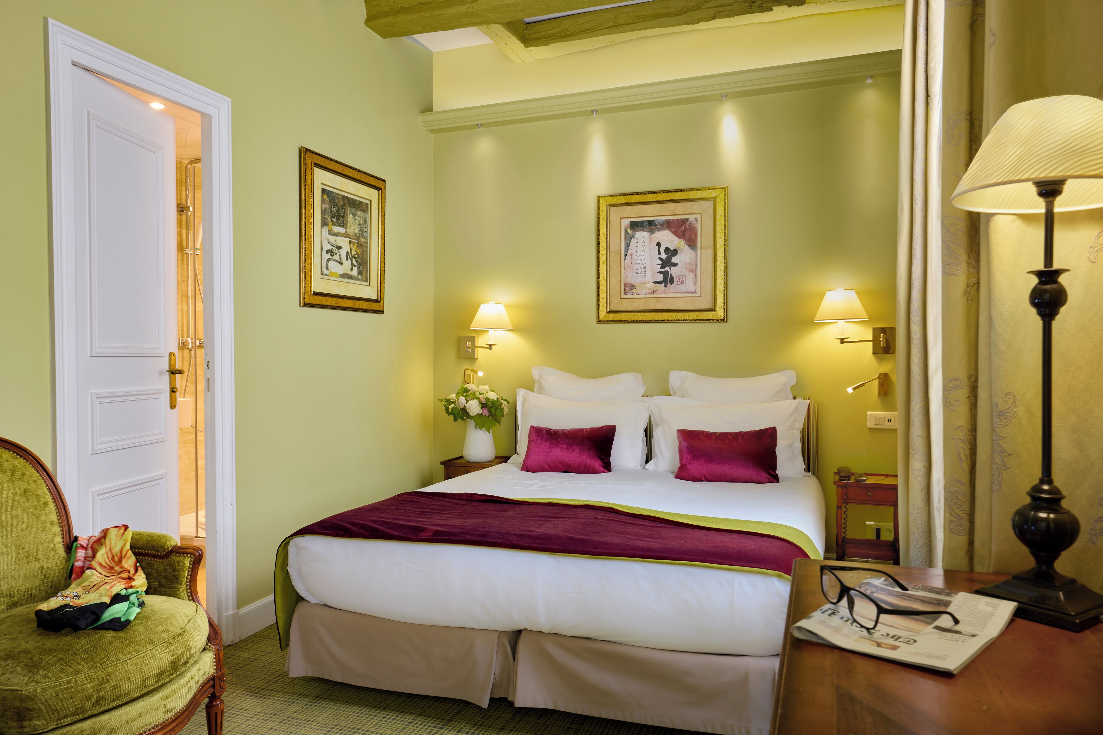 A hotel room with a bed, a chair, a nightstand, and a lamp.