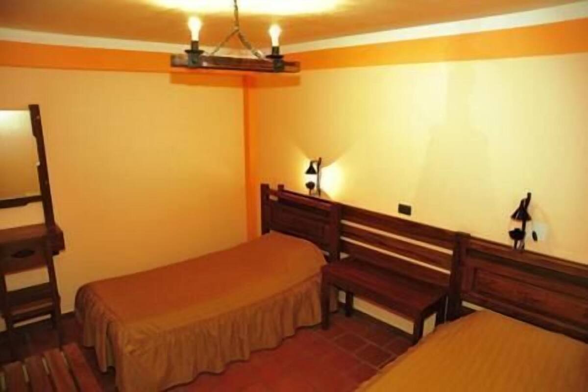 Una habitación con dos camas individuales, un banco de madera y un escritorio.