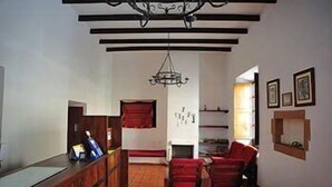 Una habitación con mostrador de recepción de madera, una silla roja, una chimenea y un candelabro.