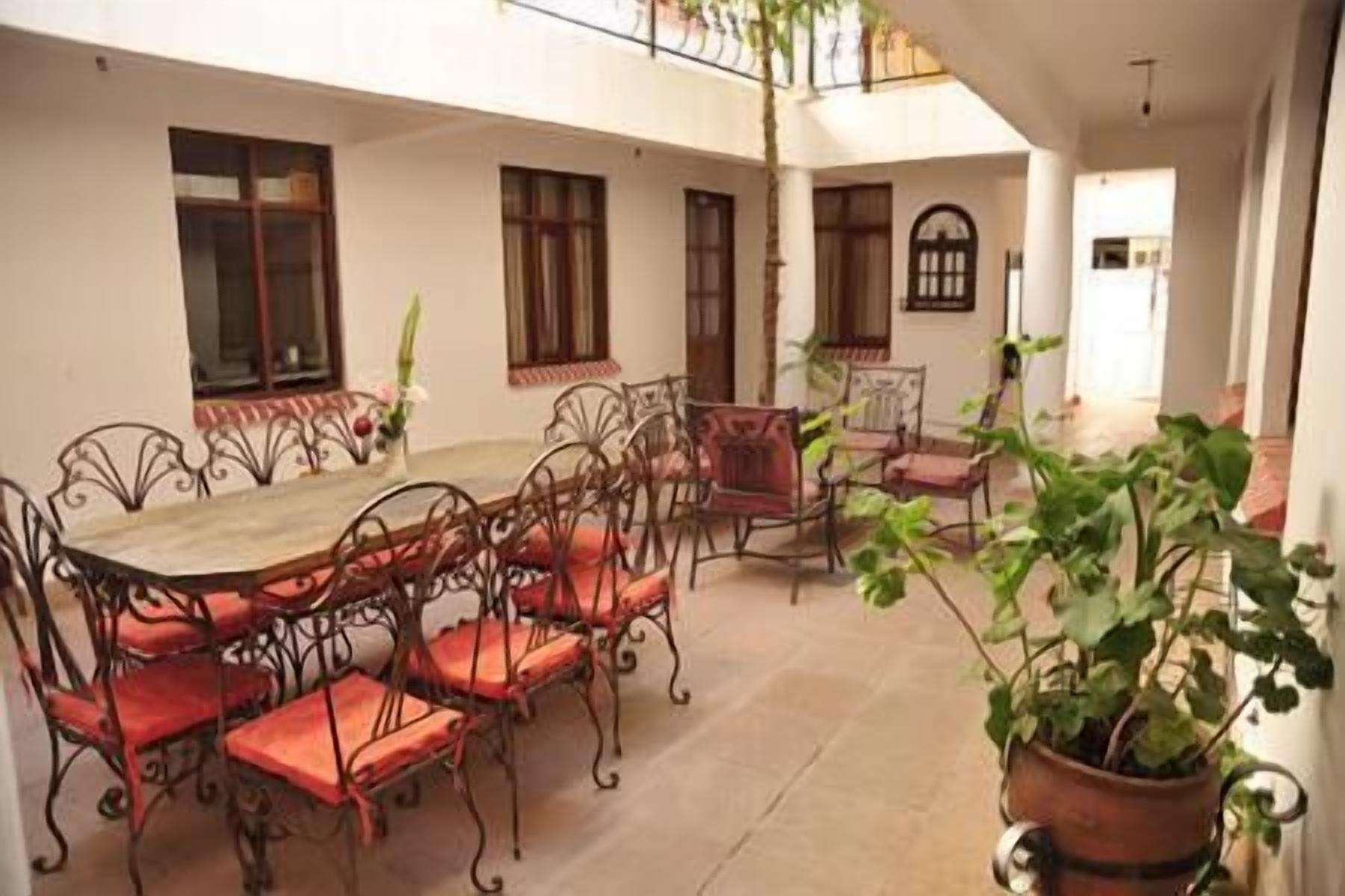 A dining area with a round table and chairs, surrounded by potted plants.