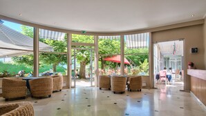 A spacious lobby with large windows, wicker furniture, and a reception desk. - Hotel Du Lac (Talloires-Montmin)