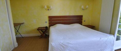 Un dormitorio con una cama grande, dos mesitas de noche, una mesita pequeña y un radiador.