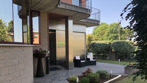 A modern building with a stone facade, a balcony, and outdoor seating. - Hotel Angi (Fosso)