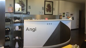 A reception desk with the name 'Angi' and framed botanical artwork on the wall. - Hotel Angi (Fosso)