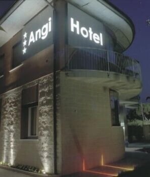 Een hotel genaamd "Angi Hotel" met een modern design, voorzien van een balkon en een gevel van steen.