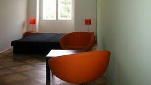 A room with a bed, a table, and two chairs. There is a window with a view of greenery outside. - Musketyr (Prague)