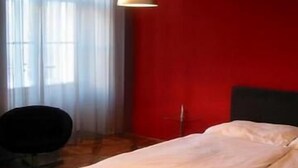 A room with a bed, a chair, and a window with sheer curtains. - Musketyr (Prague)