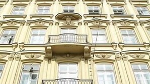 A multi-story building with ornate architectural details, including decorative moldings and a balcony with a wrought-iron railing. - Musketyr (Prague)