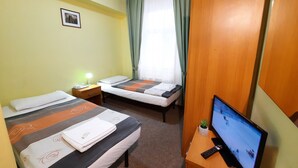 A hotel room with two beds, a desk with a TV, a nightstand, and a window with curtains. - Pension City Center (Prague)