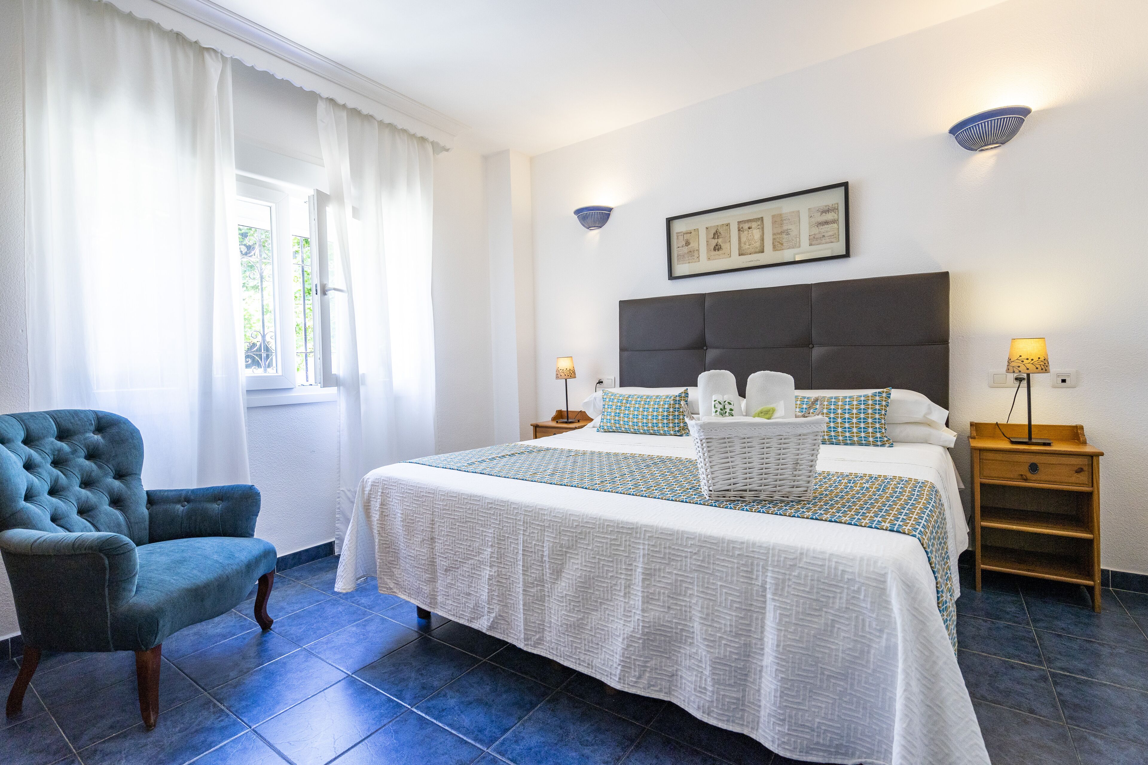 Une chambre à coucher avec un grand lit, une chaise, une table de chevet et une lampe fixée au mur.