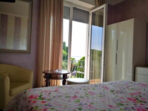Una habitación de hotel con cama, una silla, una mesa y un balcón con vistas.