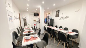 Un café moderne avec des tables blanches et des chaises noires, où l’on peut consulter un tableau affichant les différentes sortes de café et de pâtisseries proposées.