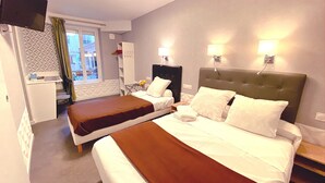 Une chambre d’hôtel avec deux lits, un bureau, une chaise et un téléviseur.
