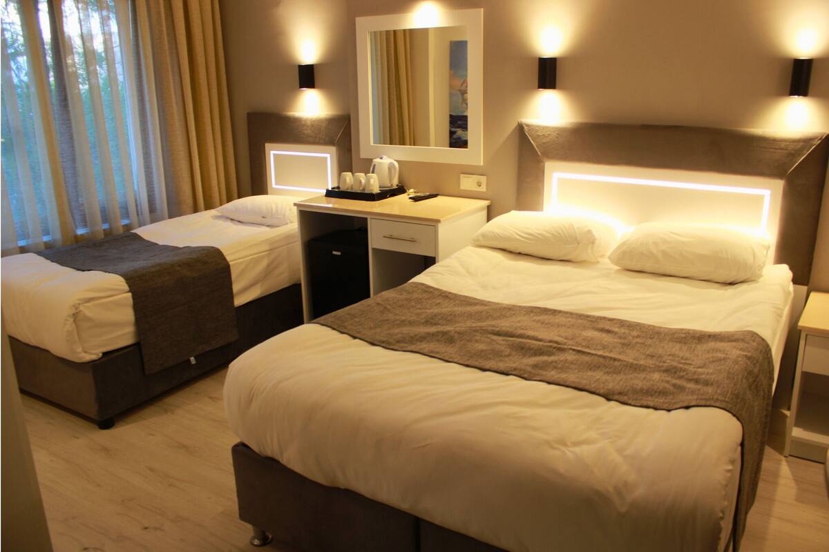 A hotel room with two single beds, a desk, a mirror, and bedside lamps.