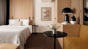 A modern hotel room with a bed, a round black table, a sofa, and a mirror. - Bob W Münchner Freiheit (Munich)