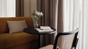 A modern room with a sofa, a round table with a vase of flowers, and a chair. - Bob W Münchner Freiheit (Munich)
